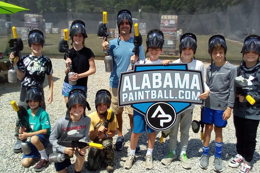 A birthday group of children with their Alabama Paintball sign