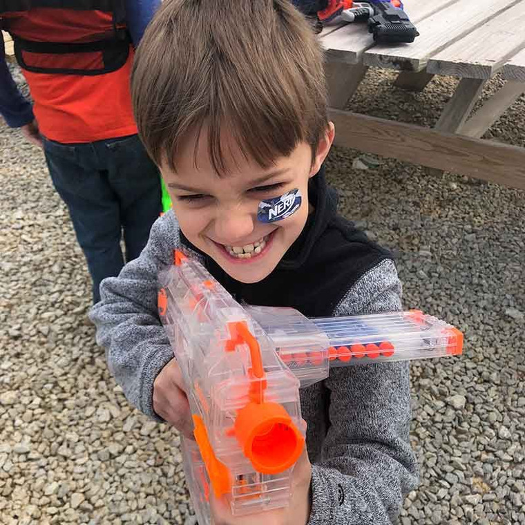 A young player with a NERF blaster and face paint